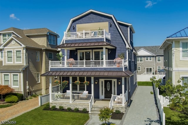 view of front of house with covered porch, a balcony, and a front yard