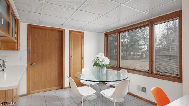 tiled dining space featuring a drop ceiling