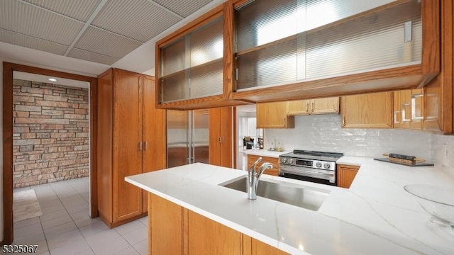 kitchen with light tile patterned flooring, sink, kitchen peninsula, and stainless steel appliances