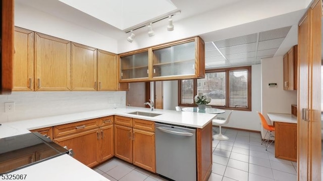 kitchen with kitchen peninsula, light tile patterned floors, stainless steel dishwasher, and sink