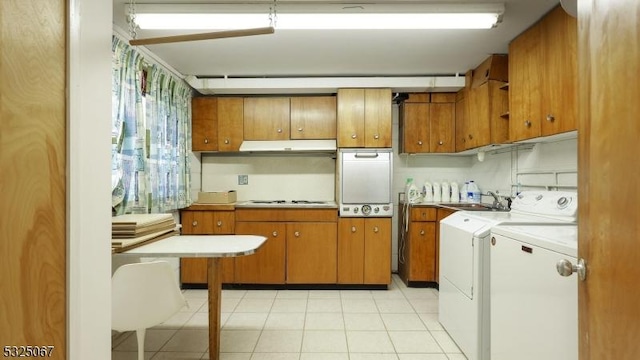 kitchen with cooktop, sink, light tile patterned floors, and washer and dryer