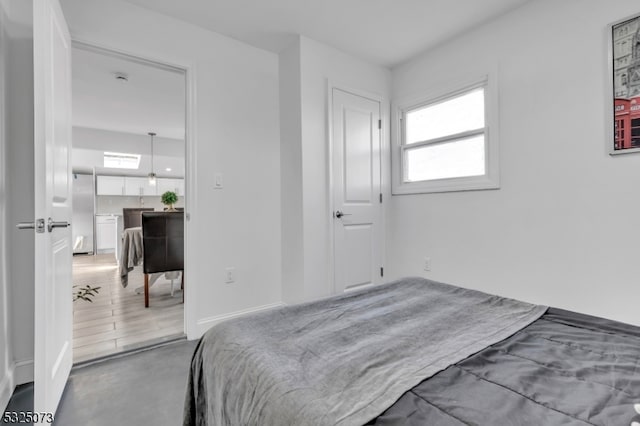 bedroom with stainless steel fridge and hardwood / wood-style flooring