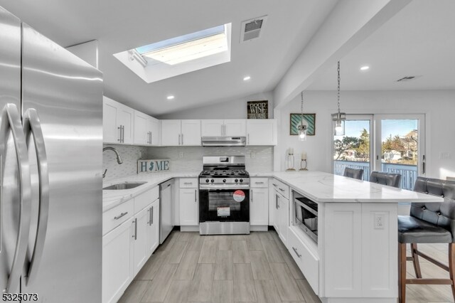 kitchen featuring kitchen peninsula, stainless steel appliances, white cabinets, and sink