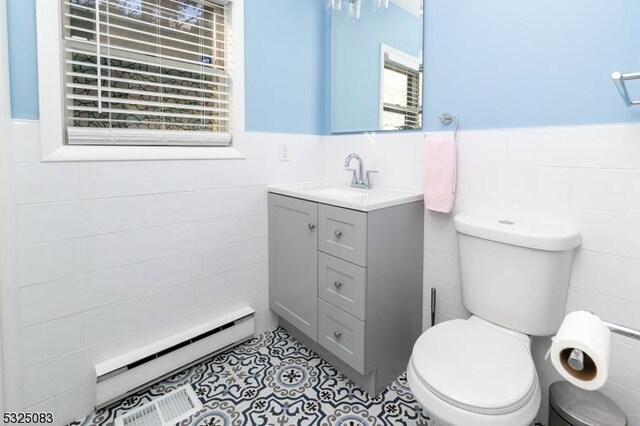 203 E Main St, Prospect Park Boro, NJ 07508 - half bathroom with tile walls, a baseboard radiator, vanity, toilet, and tile patterned flooring