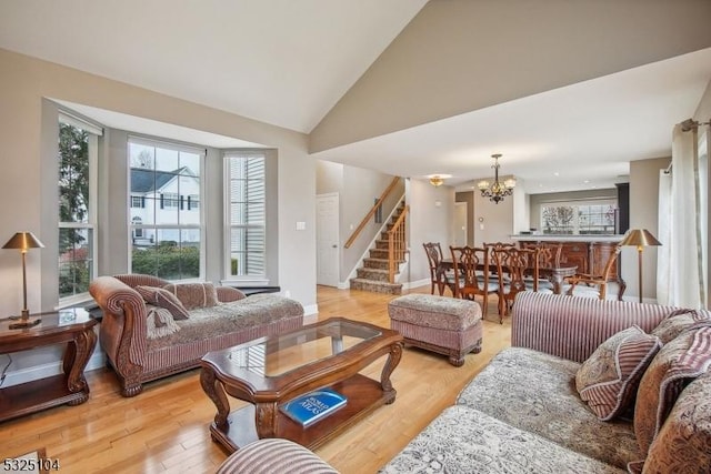 living room with plenty of natural light, light wood-type flooring, high vaulted ceiling, and a chandelier