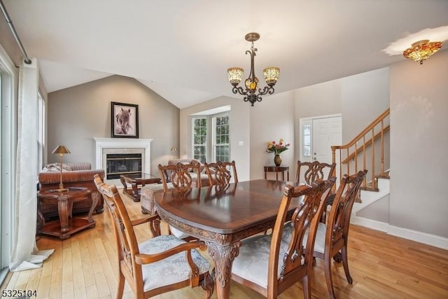 dining room featuring vaulted ceiling, light hardwood / wood-style flooring, and a notable chandelier