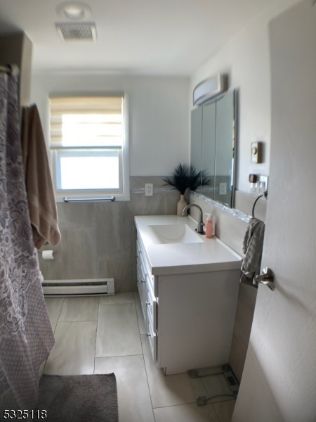 bathroom with tile patterned flooring, vanity, a baseboard radiator, and tile walls