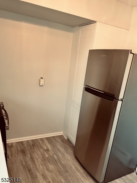 kitchen featuring hardwood / wood-style floors, white cabinets, and stainless steel refrigerator