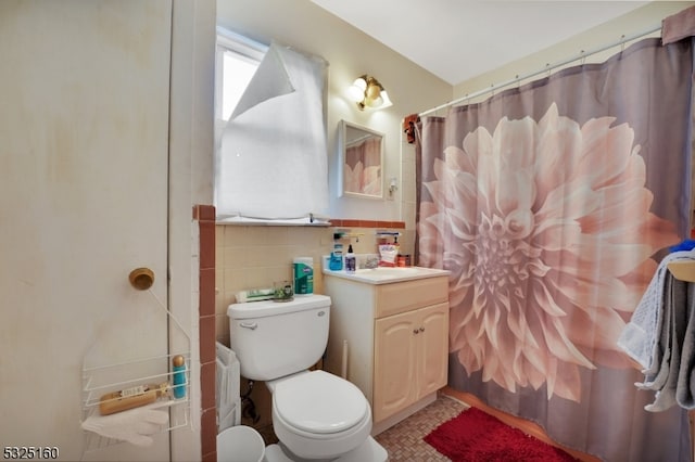 bathroom with vanity, toilet, tile walls, and walk in shower