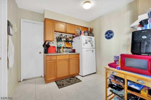 kitchen with light tile patterned floors and white refrigerator