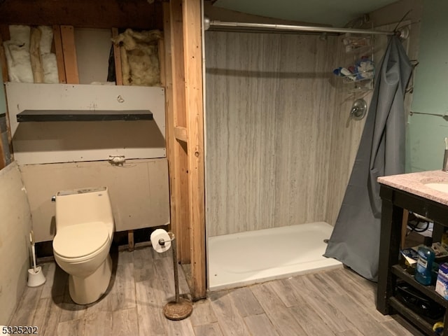 bathroom with a shower, wood-type flooring, and toilet