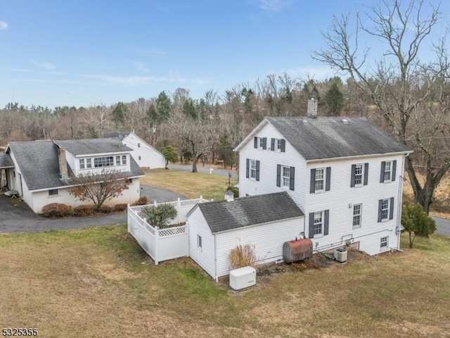 back of house with central AC and a lawn