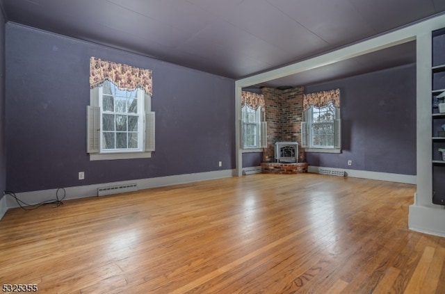 unfurnished living room with hardwood / wood-style flooring, plenty of natural light, and a wood stove