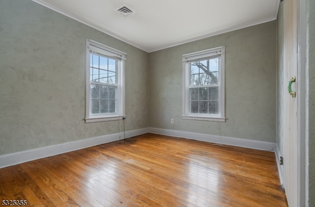 empty room featuring crown molding, plenty of natural light, and light hardwood / wood-style floors