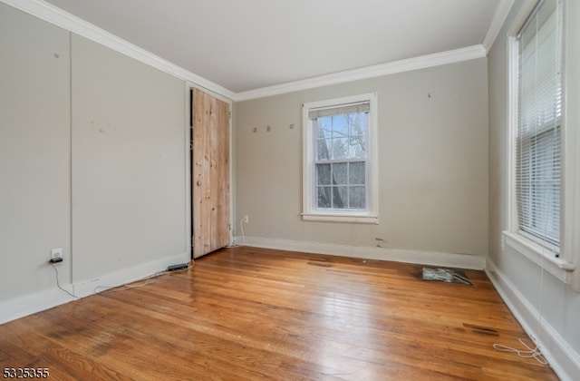 spare room with light wood-type flooring and crown molding