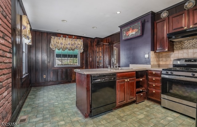 kitchen with dishwasher, sink, stainless steel gas range, tasteful backsplash, and wooden walls