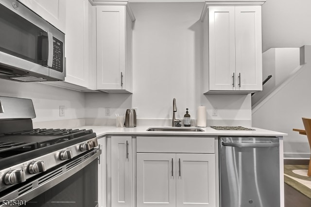 kitchen with stainless steel appliances, white cabinetry, and sink