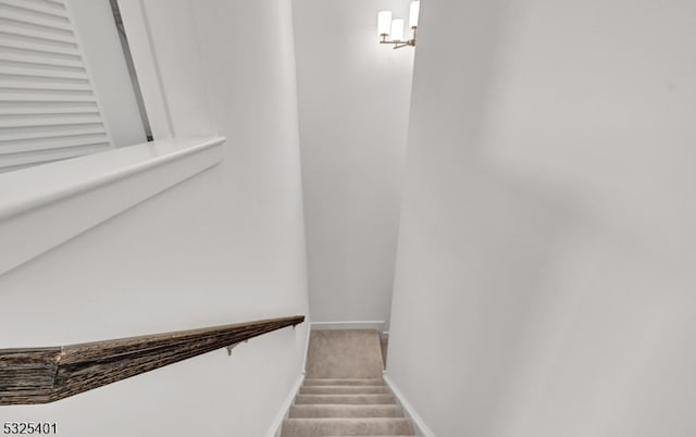 stairs with carpet flooring and a notable chandelier