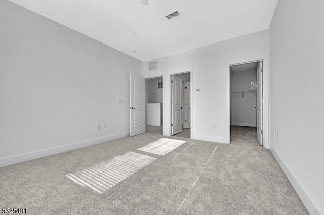 unfurnished bedroom with light colored carpet, a spacious closet, and a closet