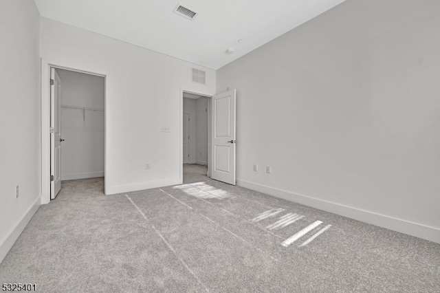 unfurnished bedroom featuring light colored carpet, a spacious closet, and a closet