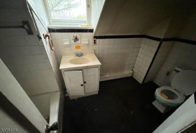 bathroom with a tub to relax in, vanity, tile walls, and toilet