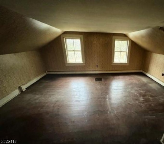 additional living space featuring plenty of natural light, dark wood-type flooring, and vaulted ceiling