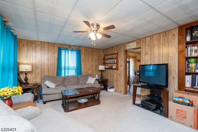 living room with ceiling fan, light carpet, and wood walls