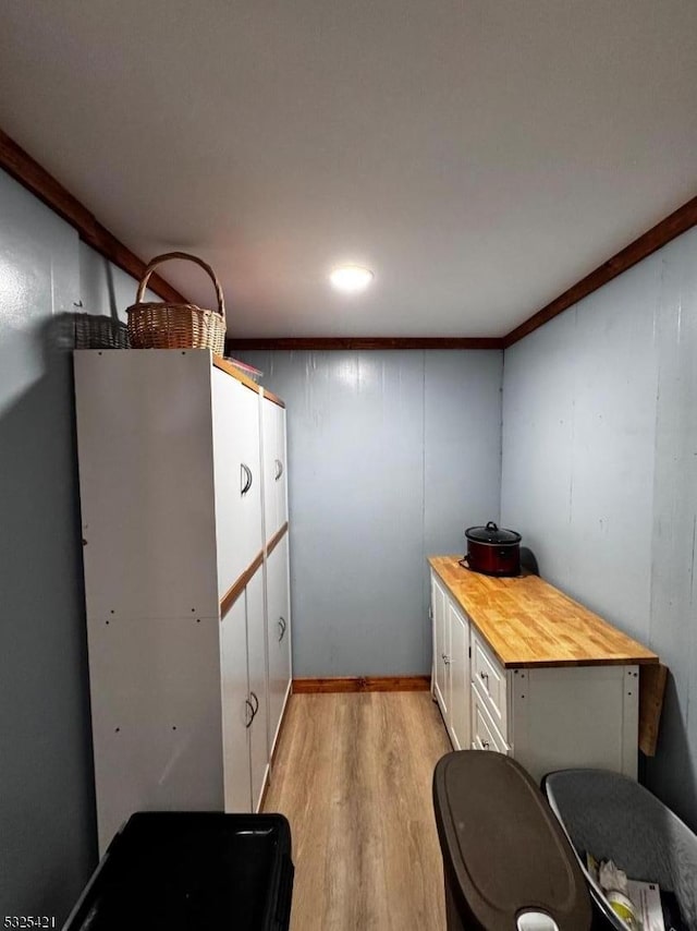 interior space with white cabinetry, crown molding, wood counters, and light hardwood / wood-style floors