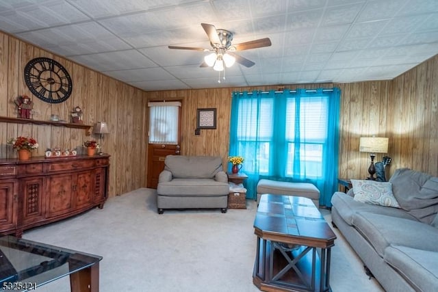 living room with ceiling fan, carpet flooring, and wood walls