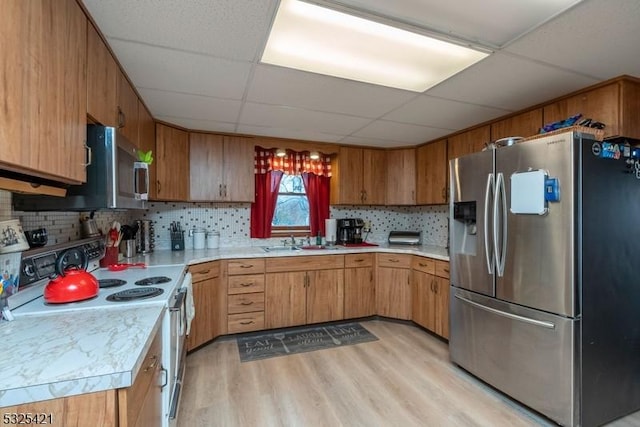 kitchen featuring appliances with stainless steel finishes, sink, backsplash, a drop ceiling, and light wood-type flooring