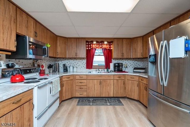 kitchen featuring decorative backsplash, a paneled ceiling, stainless steel appliances, and light hardwood / wood-style flooring