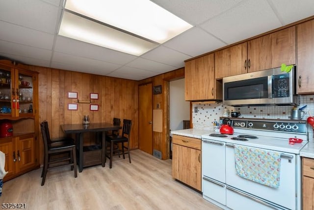 kitchen with a paneled ceiling, decorative backsplash, light hardwood / wood-style floors, and white range with electric cooktop