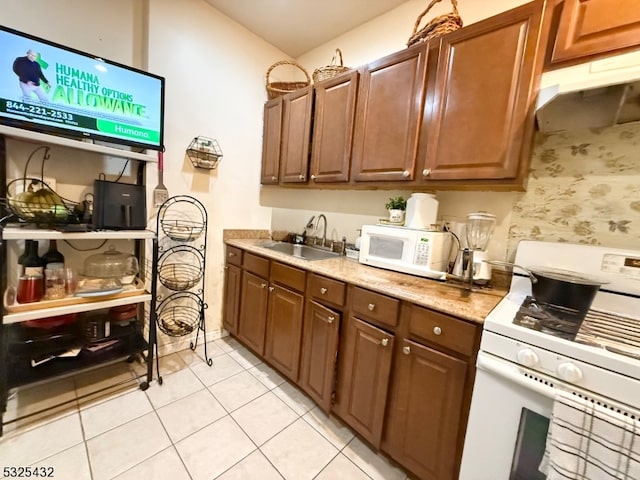 kitchen with light tile patterned flooring, white appliances, and sink