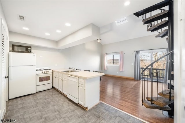 kitchen with kitchen peninsula, white appliances, white cabinetry, and sink