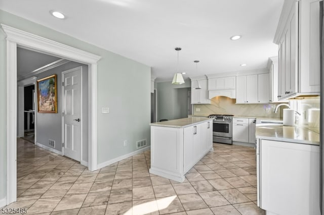 kitchen featuring stainless steel range with gas cooktop, crown molding, white cabinets, a kitchen island, and hanging light fixtures