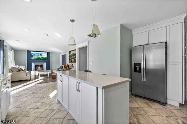 kitchen featuring light stone countertops, stainless steel fridge with ice dispenser, a large fireplace, and white cabinetry