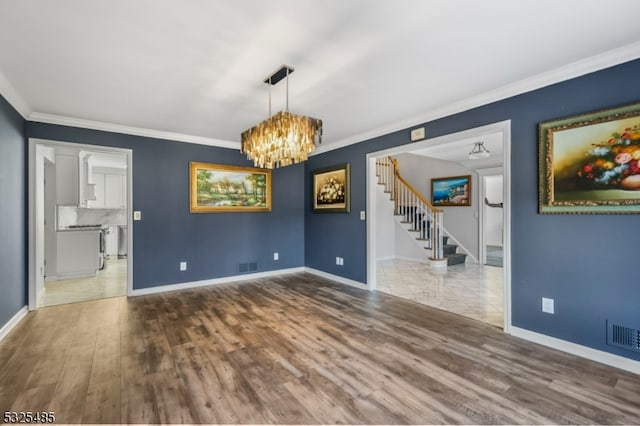 unfurnished dining area with a notable chandelier, wood-type flooring, and ornamental molding