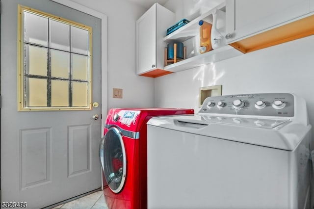 washroom featuring cabinets, light tile patterned floors, and washing machine and dryer