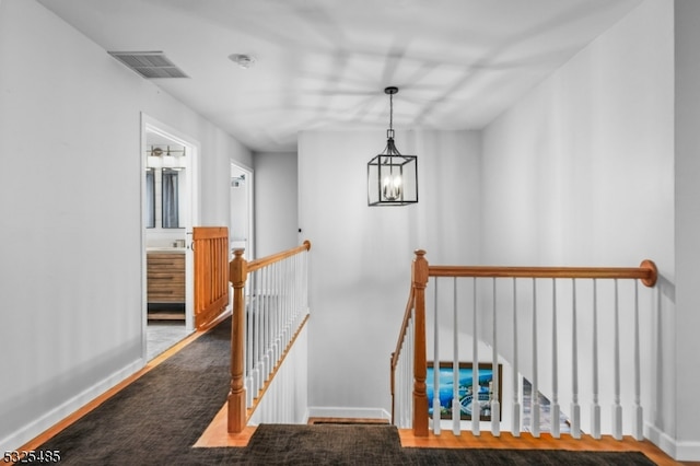 staircase featuring hardwood / wood-style floors and a notable chandelier