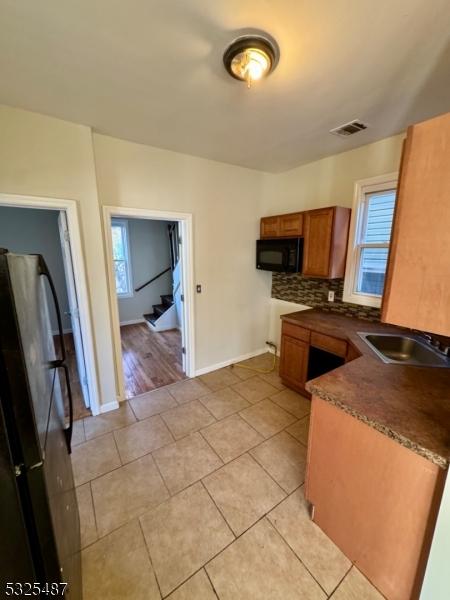 kitchen with light tile patterned flooring, stainless steel fridge, tasteful backsplash, and sink