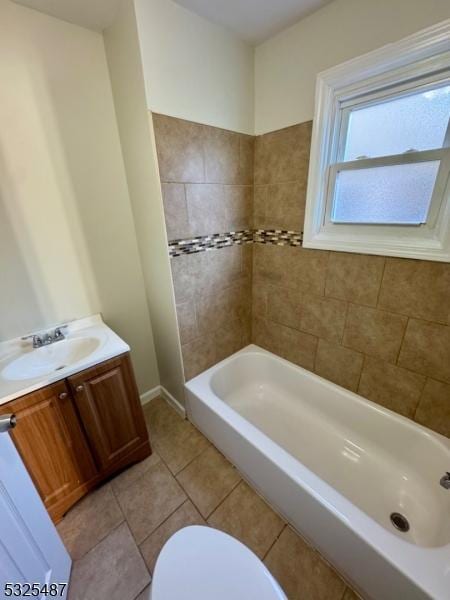 full bathroom featuring tile patterned flooring, vanity, tiled shower / bath combo, and toilet