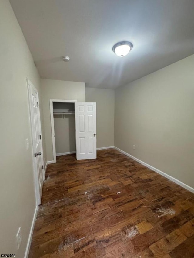 unfurnished bedroom with dark hardwood / wood-style floors and a closet