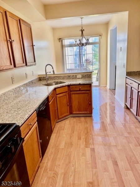 kitchen with sink, hanging light fixtures, light wood-type flooring, a notable chandelier, and kitchen peninsula