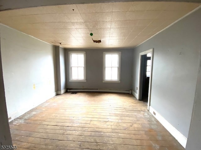 spare room featuring a baseboard radiator and light wood-type flooring