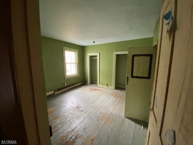 empty room featuring baseboard heating and light wood-type flooring