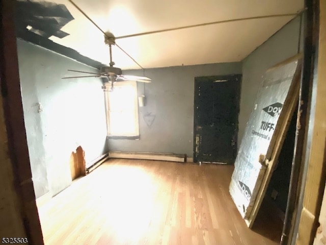 unfurnished room featuring ceiling fan, baseboard heating, and light hardwood / wood-style flooring