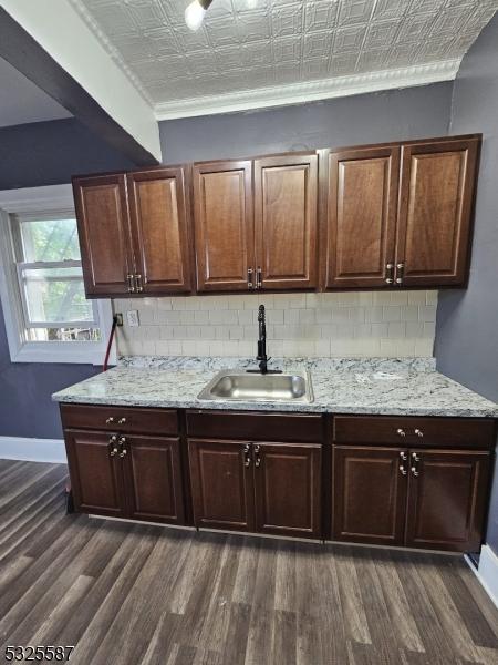 kitchen with dark hardwood / wood-style flooring, dark brown cabinetry, sink, and ornamental molding