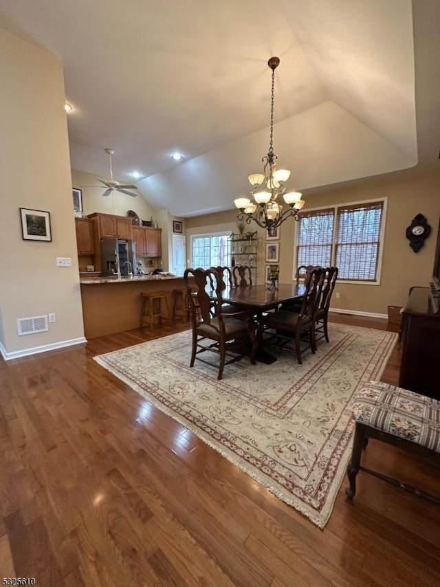 dining space with hardwood / wood-style flooring, ceiling fan with notable chandelier, and lofted ceiling