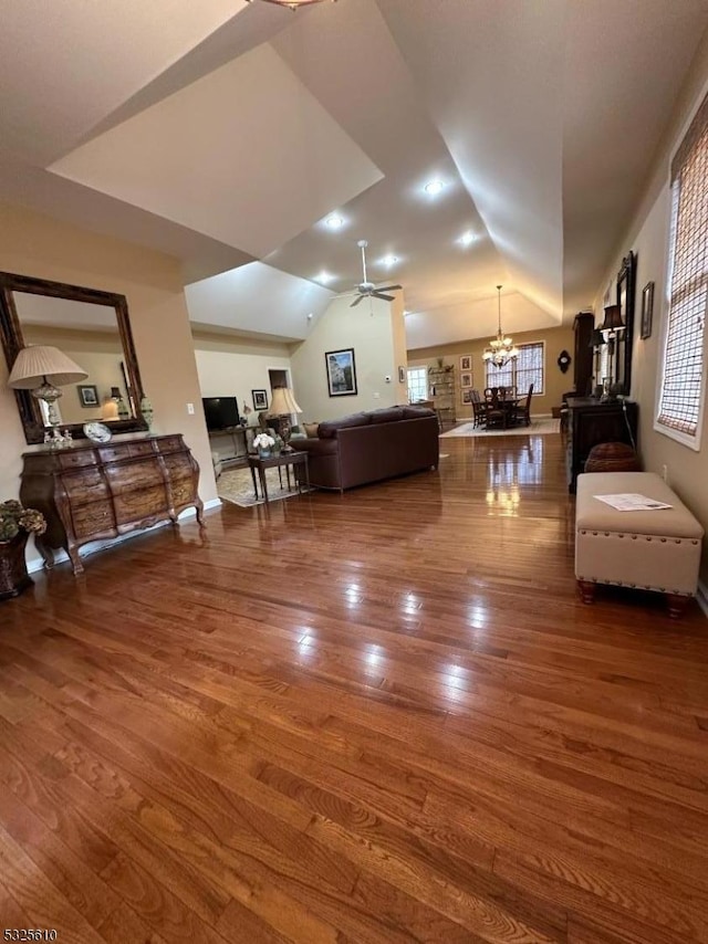 living room with hardwood / wood-style floors, plenty of natural light, ceiling fan with notable chandelier, and vaulted ceiling