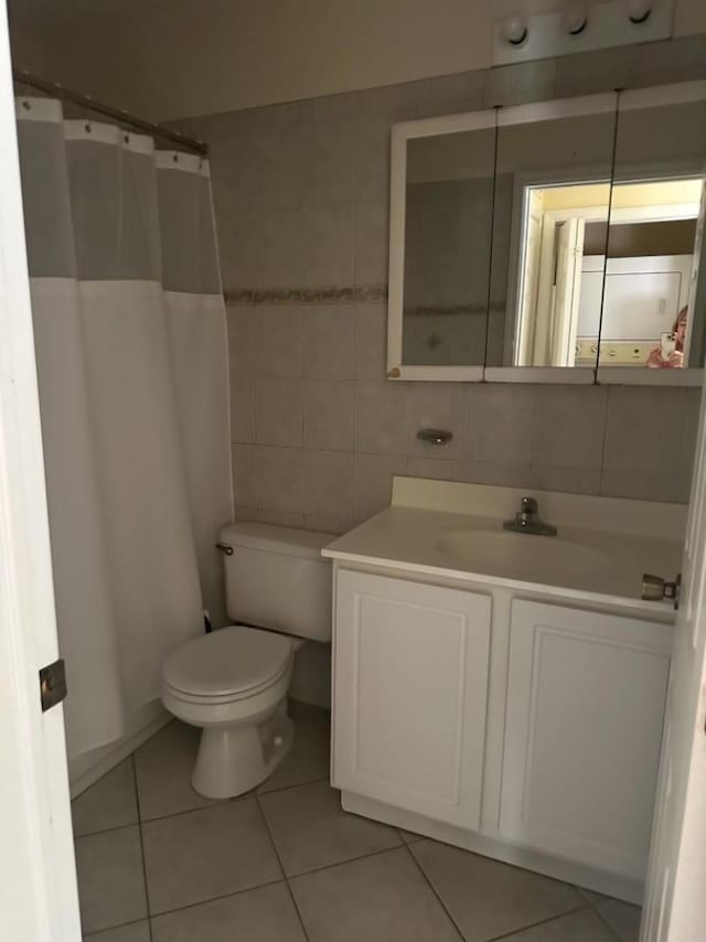 bathroom with vanity, tile patterned floors, toilet, tile walls, and tasteful backsplash